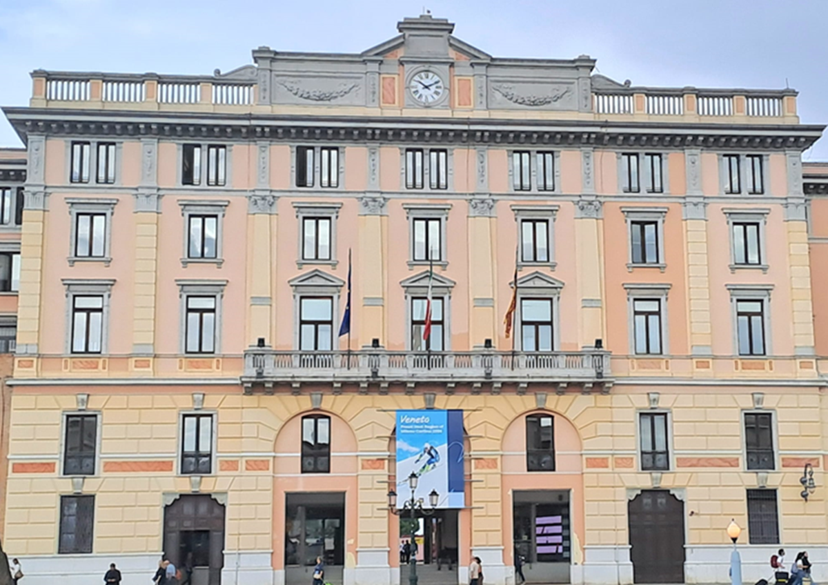 Facciata del Palazzo Grandi Stazioni a Venezia con manifesto dei Giochi Olimpici e Paralimpici Invernali di Milano Cortina 2026