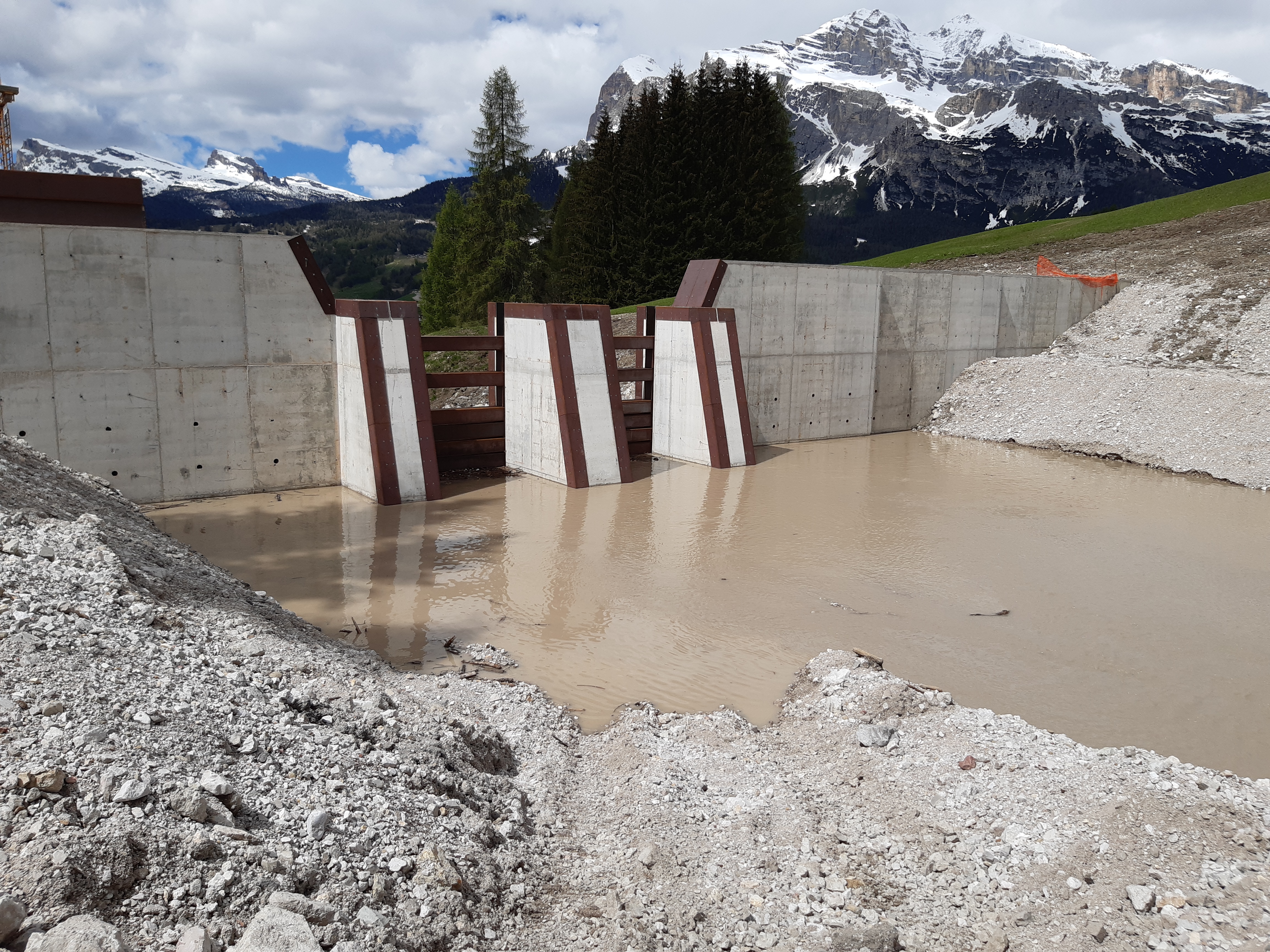 opere in cemento armato sul torrente bigontina sfondo con montagne innevate